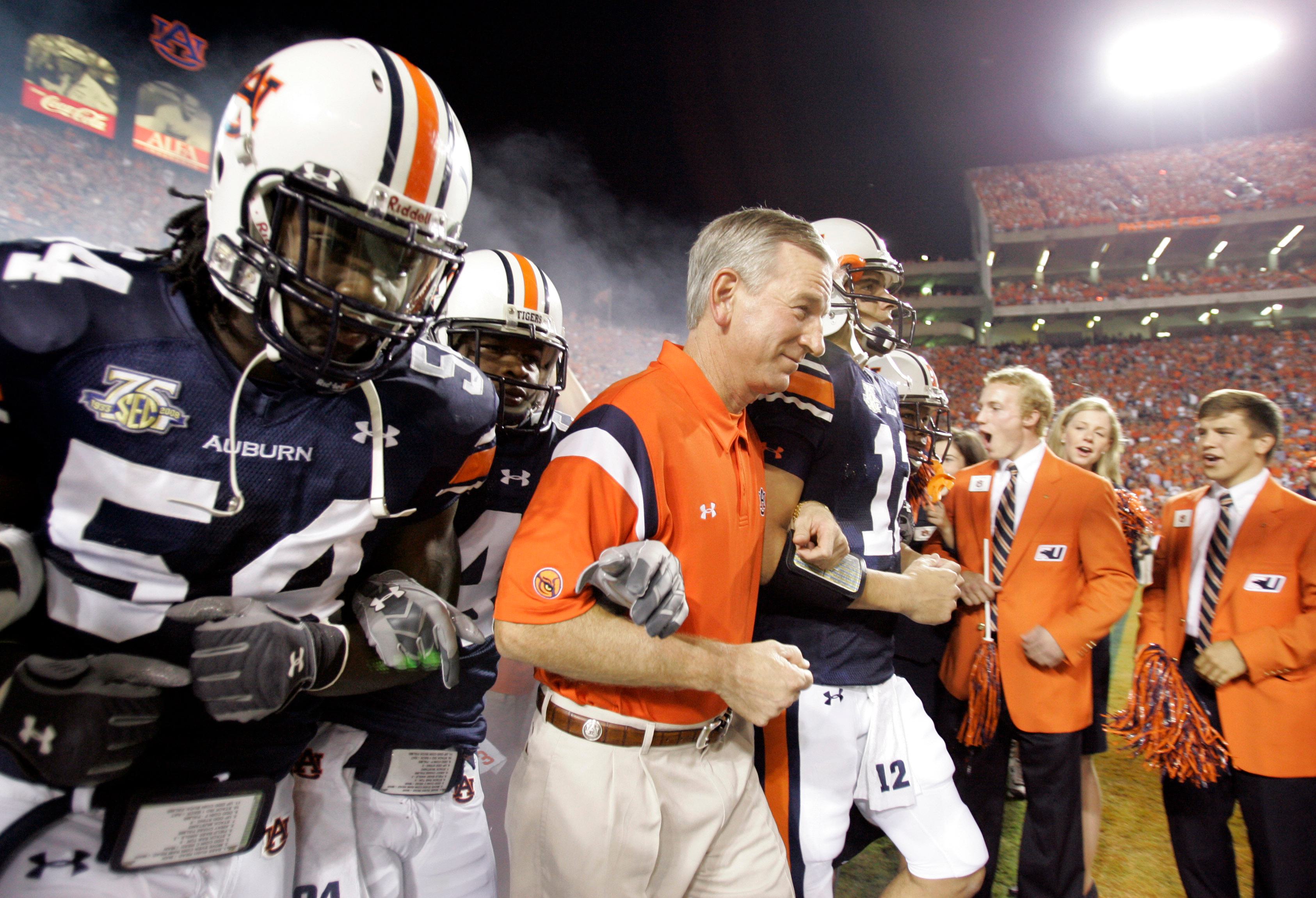 Auburn coach Tommy Tuberville, center, leads players Quentin Groves, left, and Brandon Cox, right, onto the field before the start of a football game against South Florida, Saturday Sept. 8, 2007, in Auburn, Ala.
