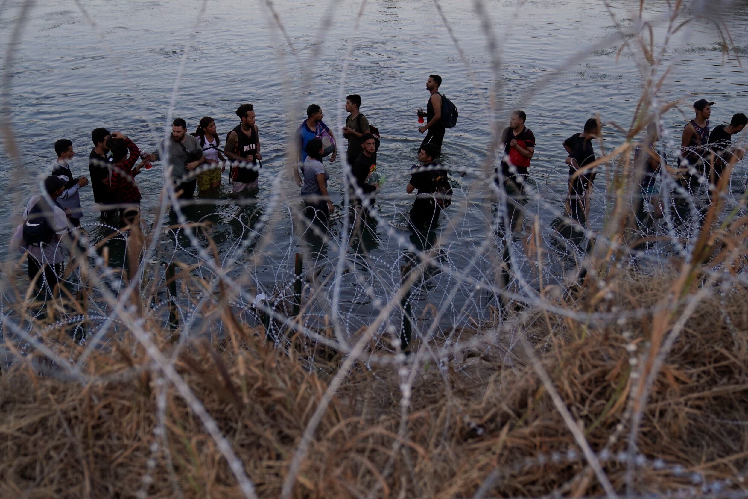 Migrants wait to climb over concertina wire after they crossed the Rio Grande and entered the U.S. from Mexico, Saturday, Sept. 23, 2023, in Eagle Pass, Texas.