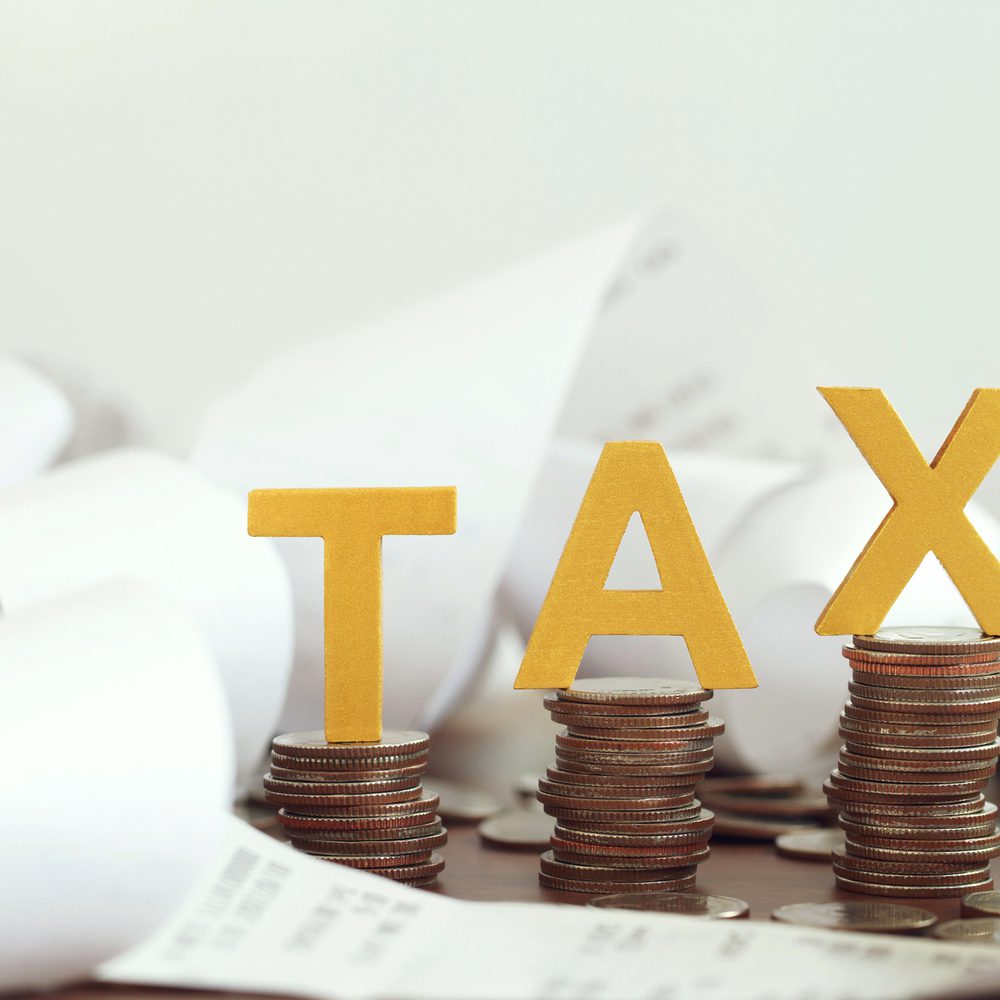 Word tax put on stacked coins and bills on the wooden table.Tax time Alabama News