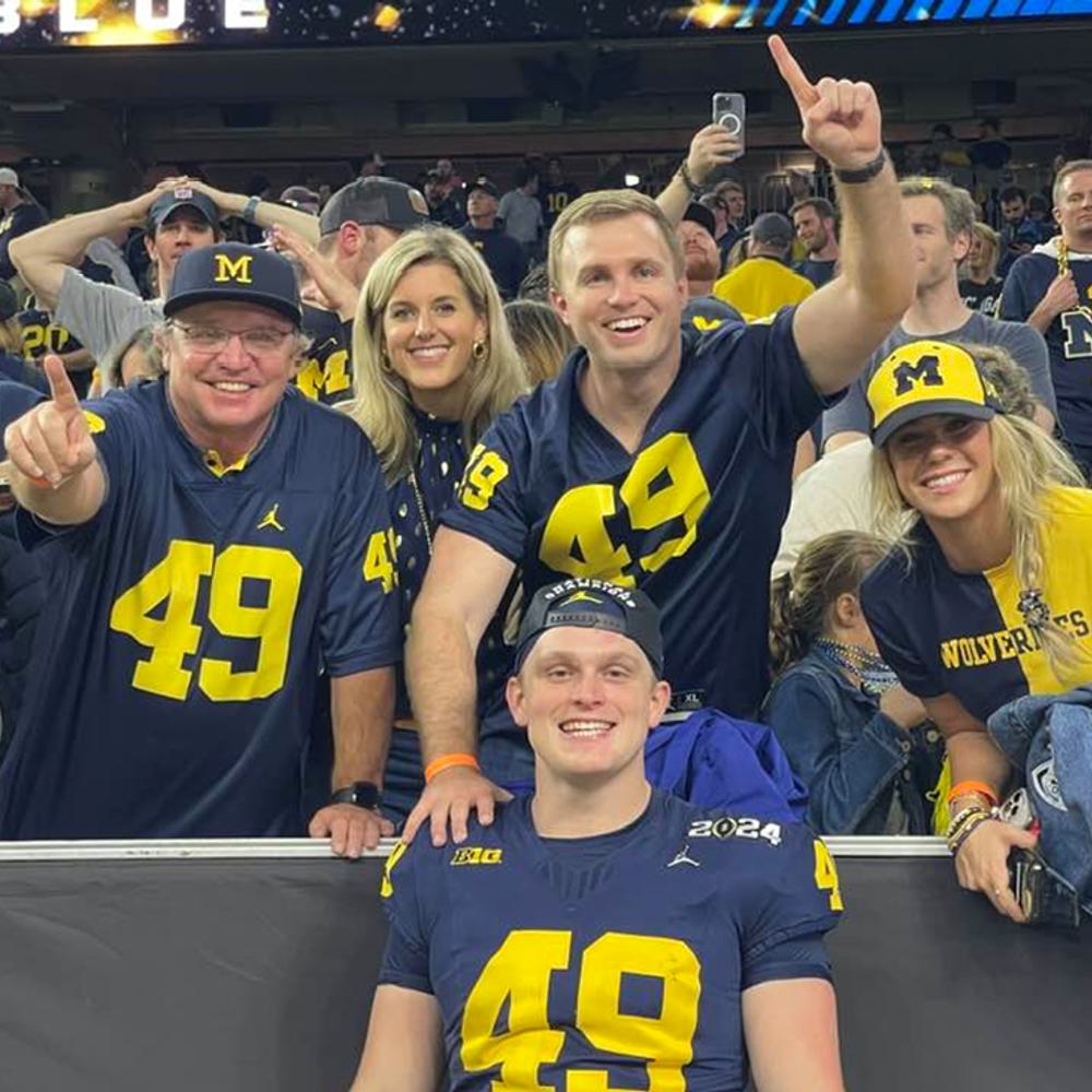 Mobile attorney “Uncle Desi” Tobias with right hand pointing forward with family of his nephew, William Wagner, front center, after Michigan CFP victory. Alabama News